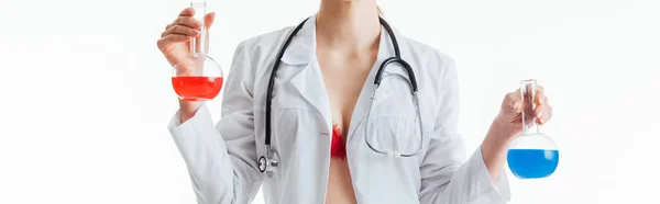 Panoramic shot of sexy nurse holding flasks with red and blue liquid isolated on white — Stock Photo