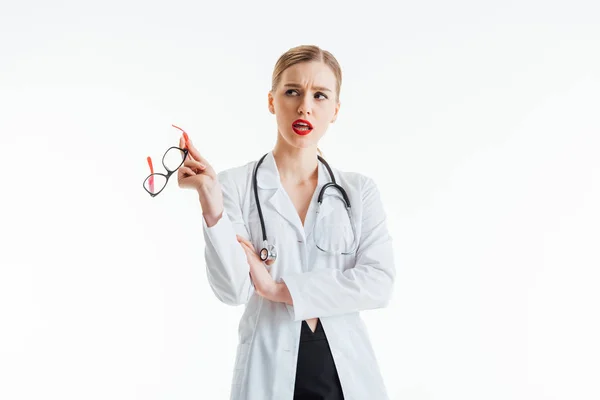 Задумлива сексуальна медсестра тримає окуляри і дивиться ізольовано на білому — стокове фото