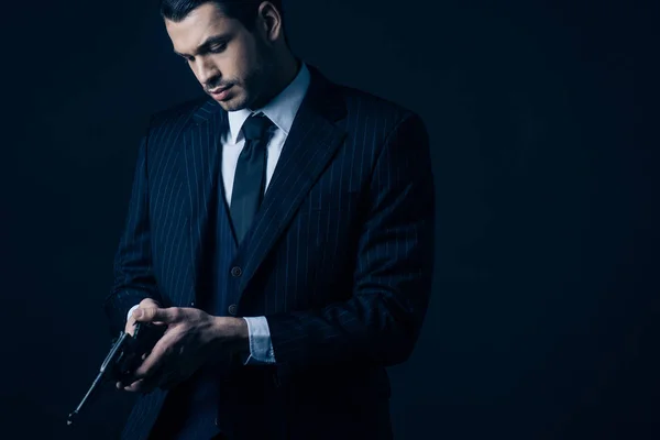 Gángster en traje elegante cargando revólver sobre fondo negro - foto de stock