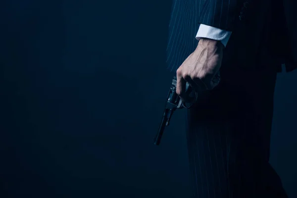 Vista cortada de gangster segurando arma no fundo escuro — Fotografia de Stock