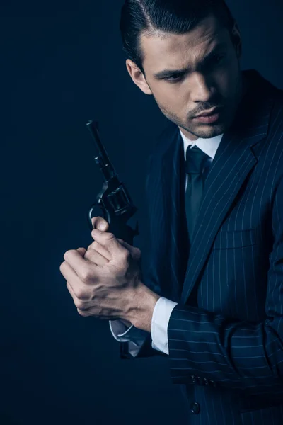 Gangster holding weapon with clenched hands on dark blue — Stock Photo