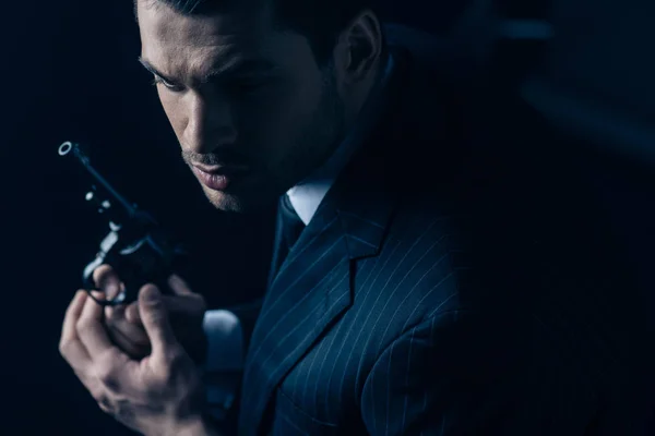 Gangster com revólver em mãos apertadas sobre fundo escuro — Fotografia de Stock