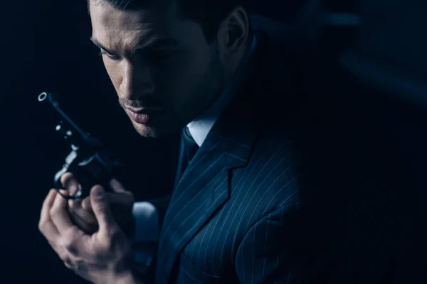 Gangster avec revolver dans les mains serrées sur fond sombre — Photo de stock