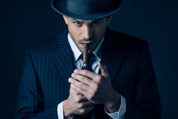 Mafioso zündet Zigarre an und blickt in Kamera auf dunklem Hintergrund — Stockfoto