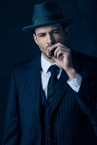 Vista frontal del cigarro fumador mafioso sobre fondo oscuro - foto de stock