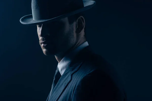 Portrait of mafioso in felt hat and suit on dark blue background — Stock Photo