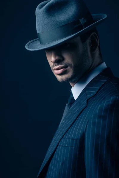 Mafioso en traje y sombrero de fieltro sobre fondo azul oscuro - foto de stock