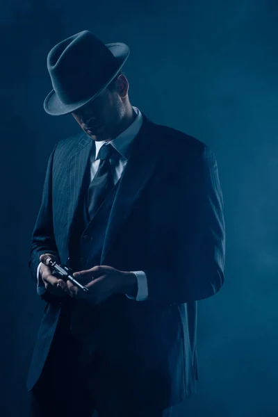 Gangster avec revolver dans les mains sur fond bleu foncé — Photo de stock