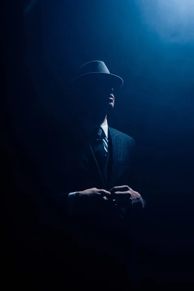 Silhouette of mafioso buttoning up on dark blue background — Stock Photo