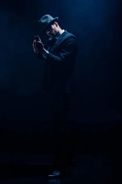 Gangster with clenched hands aiming weapon on dark blue background — Stock Photo