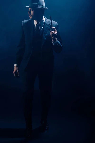 Gangster raising gun and looking away on dark background — Stock Photo