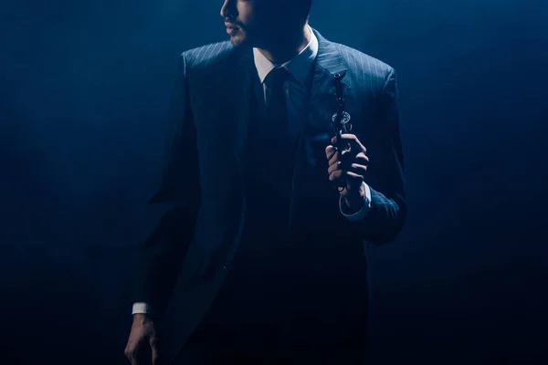 Vue recadrée de Gangster soulevant revolver et regardant loin sur fond sombre — Photo de stock