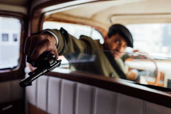 Foco seletivo do perigoso gangster apontando revólver no carro — Fotografia de Stock