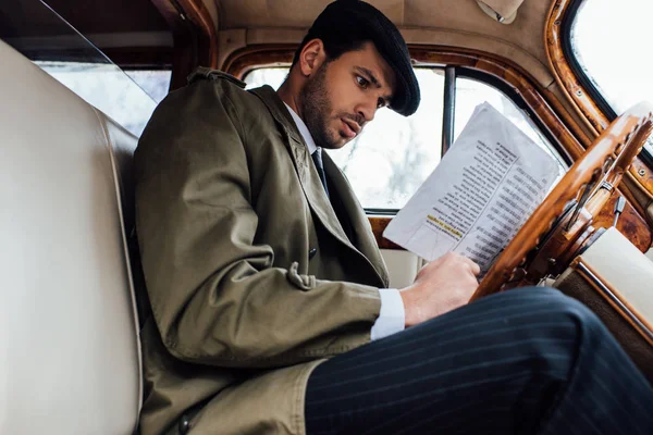 Vista de bajo ángulo de mafioso mirando el periódico en el coche — Stock Photo