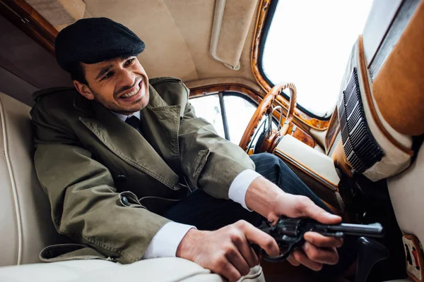 Low angle view of tense mafioso with gun in ambush sitting in car — Stock Photo