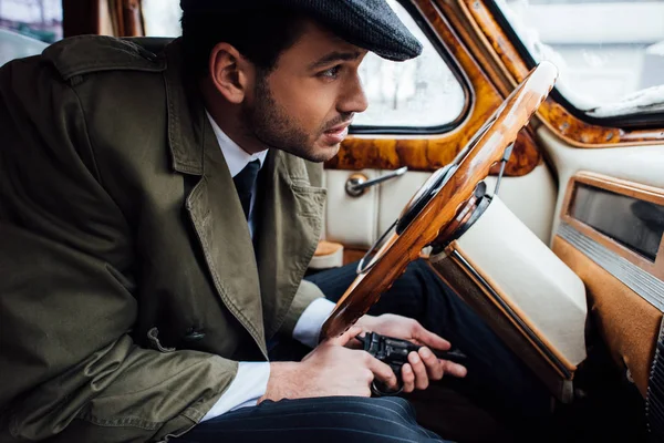 Selective focus of mafioso with gun in ambush sitting in car — Stock Photo