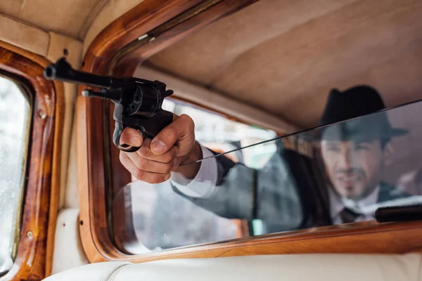 Enfoque selectivo de pistola de tiro gangster con la mano extendida de coche retro - foto de stock