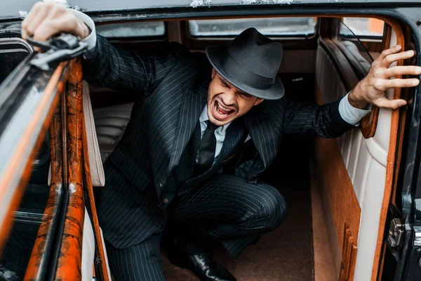 Selective focus of scared mafioso sitting in ambush with revolver in car — Stock Photo