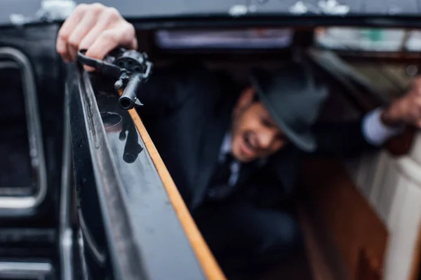 Enfoque selectivo del gángster sentado en emboscada con revólver en coche - foto de stock