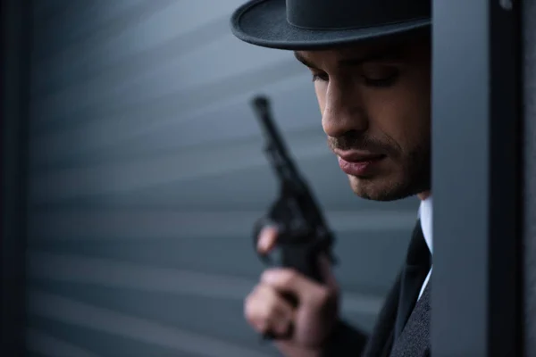 Concentration sélective de gangster avec arme dans un coin près du mur sur la rue — Photo de stock