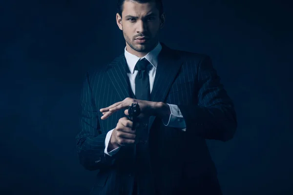 Frontansicht des Gangsters, der auf Gewehrlauf zielt und auf dunkelblaue Kamera blickt — Stockfoto