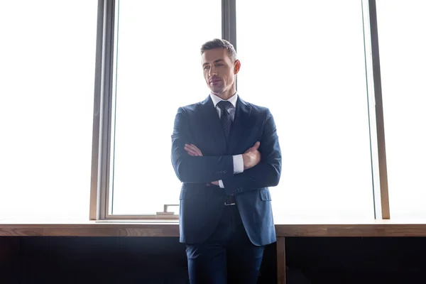 Businessman in suit with crossed arms looking away in hotel — Stock Photo