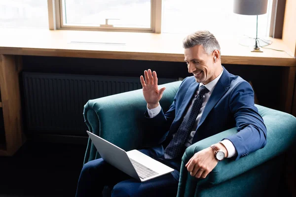 High angle view of smiling businessman in suit waving during video call — Stock Photo