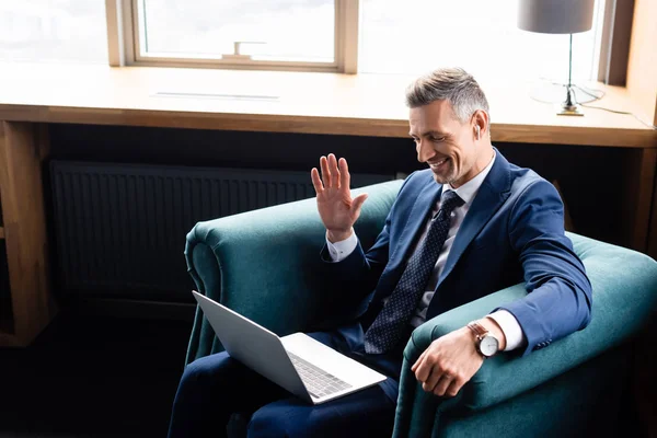 Vue grand angle de l'homme d'affaires souriant en costume agitant pendant l'appel vidéo — Photo de stock