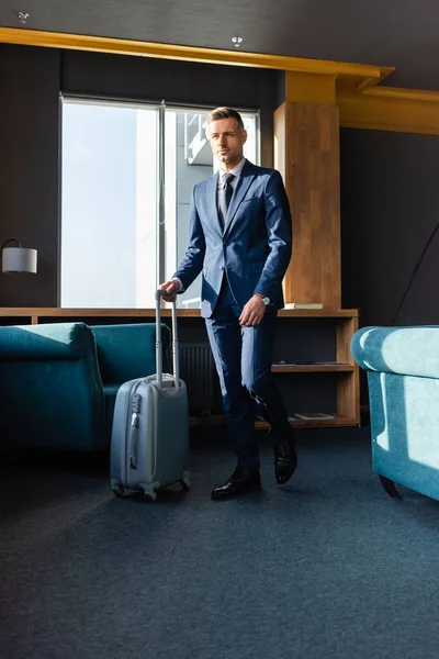Hombre de negocios guapo de traje caminando con bolsa de viaje en el hotel - foto de stock