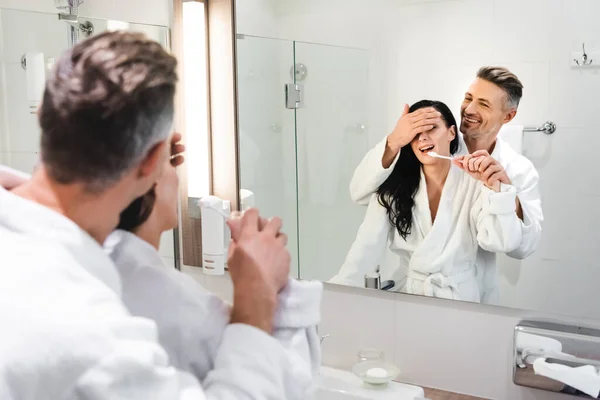 Foco selectivo de novio obscurecer la cara de la novia sonriente con cepillo de dientes en el hotel - foto de stock