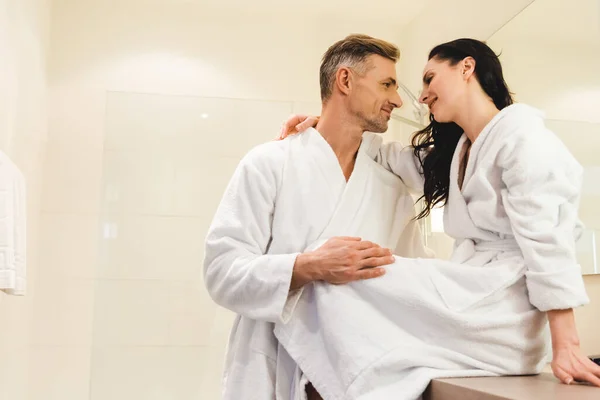 Sorrindo namorado e namorada em roupões de banho abraçando no hotel — Fotografia de Stock