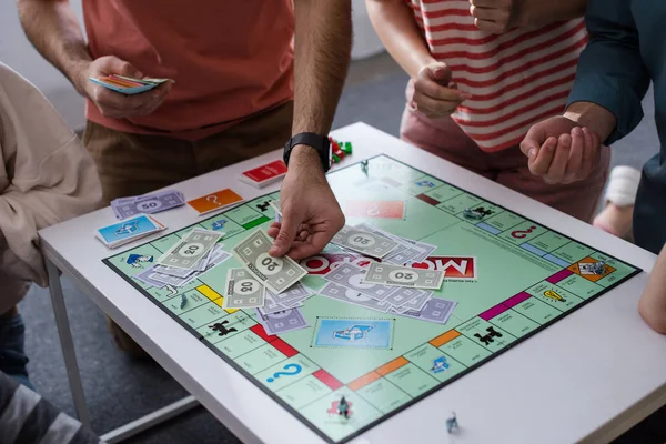 KYIV, UKRAINE - JANUARY 27, 2020: cropped view of man taking card while playing monopoly game with friends — Stock Photo