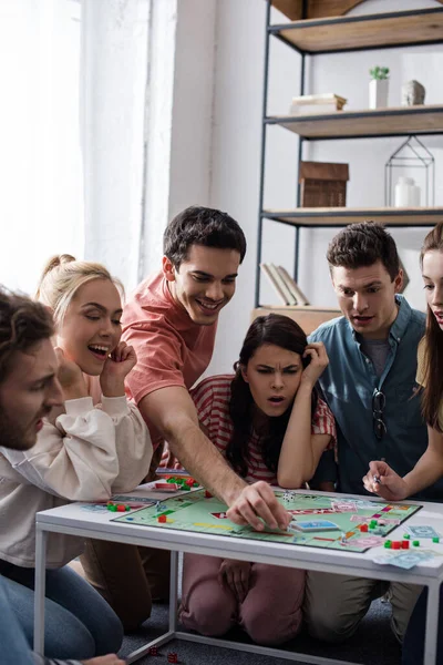 KYIV, UKRAINE - JANUARY 27, 2020: shocked girl playing monopoly game with smiling friends — Stock Photo