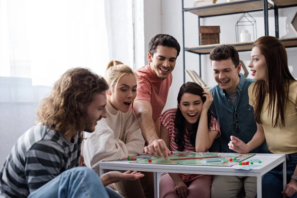 KYIV, UCRANIA - 27 de enero de 2020: jóvenes amigos emocionados jugando al juego del monopolio en casa - foto de stock