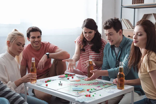 KYIV, UKRAINE - JANUARY 27, 2020: angry girl and man pointing with hands while playing monopoly game with smiling friends — Stock Photo