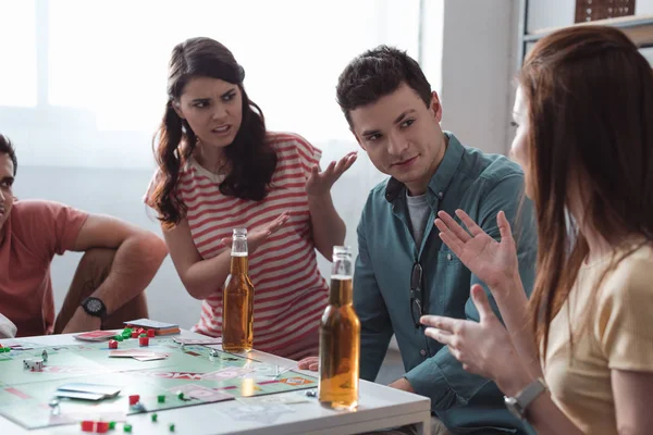 Kiew, Ukraine - 27. Januar 2020: unzufriedene Mädchen gestikulieren beim Monopoly-Spiel in der Nähe eines verwirrten Mannes — Stockfoto