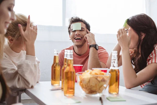 Cheerful man with sticky note on forehead playing name game with friends — Stock Photo