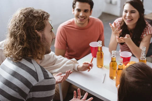 Enfoque selectivo del hombre con nota adhesiva en la frente jugando juego de nombre con amigos alegres - foto de stock