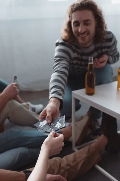 QUIIV, UCRÂNIA - JANEIRO 27, 2020: homem alegre tomando cartão enquanto joga jogo de máfia com amigos — Stock Photo