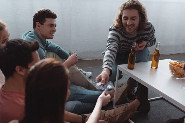 KYIV, UCRANIA - 27 de enero de 2020: hombre sonriente tomando cartas mientras juega al juego de la mafia con amigos - foto de stock