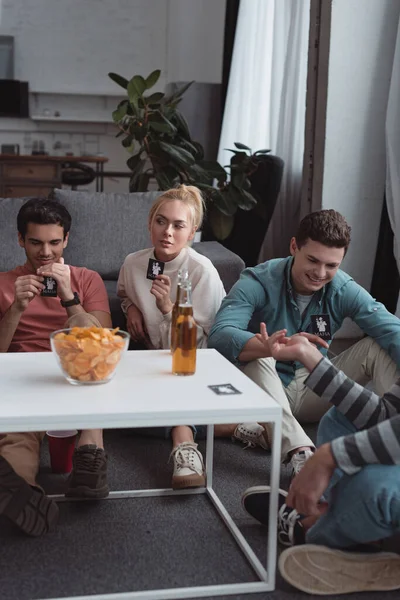 KYIV, UKRAINE - JANUARY 27, 2020: young friends playing mafia game while sitting near table with chips and beer — Stock Photo