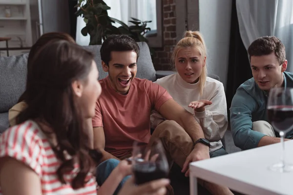 Ragazza seria che indica con mano mentre si siede vicino a amici allegri — Stock Photo