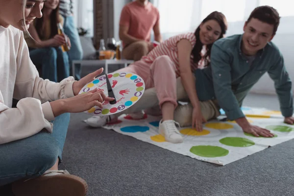 KYIV, UKRAINE - JANEIRO 27, 2020: foco seletivo de menina segurando move tabuleiro enquanto amigos alegres jogando jogo twister — Fotografia de Stock