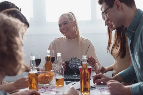 KYIV, UKRAINE - JANEIRO 27, 2020: amigos alegres que jogam loteria enquanto se sentam à mesa com bebidas e batatas fritas — Fotografia de Stock