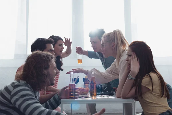 KYIV, UKRAINE - 27 JANVIER 2020 : Des amis en colère se disputent alors qu'ils sont assis à table avec un distributeur de boules de loto — Photo de stock