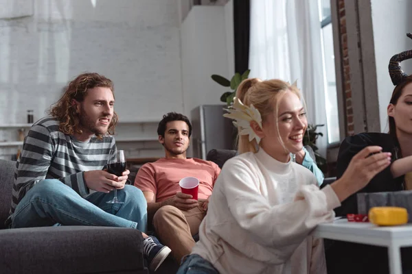 Uomini attenti guardando le ragazze sorridenti in costumi fata gioco da tavolo — Foto stock