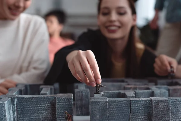 KYIV, UKRAINE - JANEIRO 27, 2020: foco seletivo de menina sorridente segurando estatueta de brinquedo enquanto joga labirinto jogo de tabuleiro — Fotografia de Stock