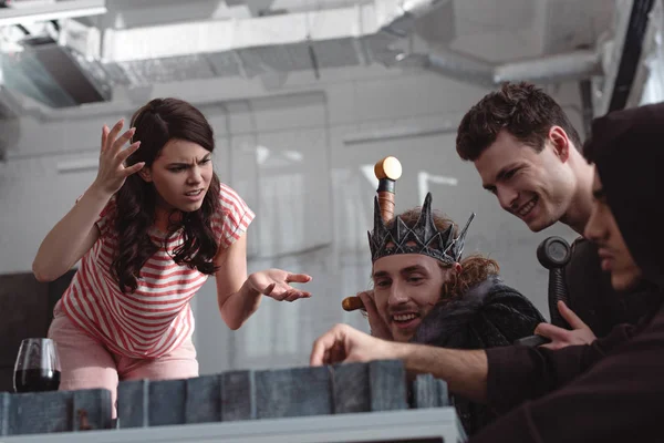 КИЕВ, УКРАИНА - 27 ЯНВАРЯ 2020: недовольная девушка жестикулирует рядом с весёлыми друзьями, играя в настольную игру в сказочных костюмах — стоковое фото