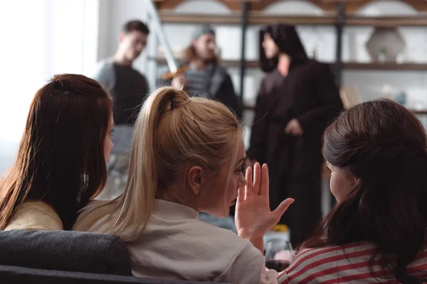 Selective focus of girls sitting on sofa and young men in fairy costumes — Stock Photo