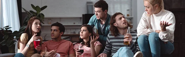 Panoramic shot of excited friends talking and gesturing while sitting at home — Stock Photo